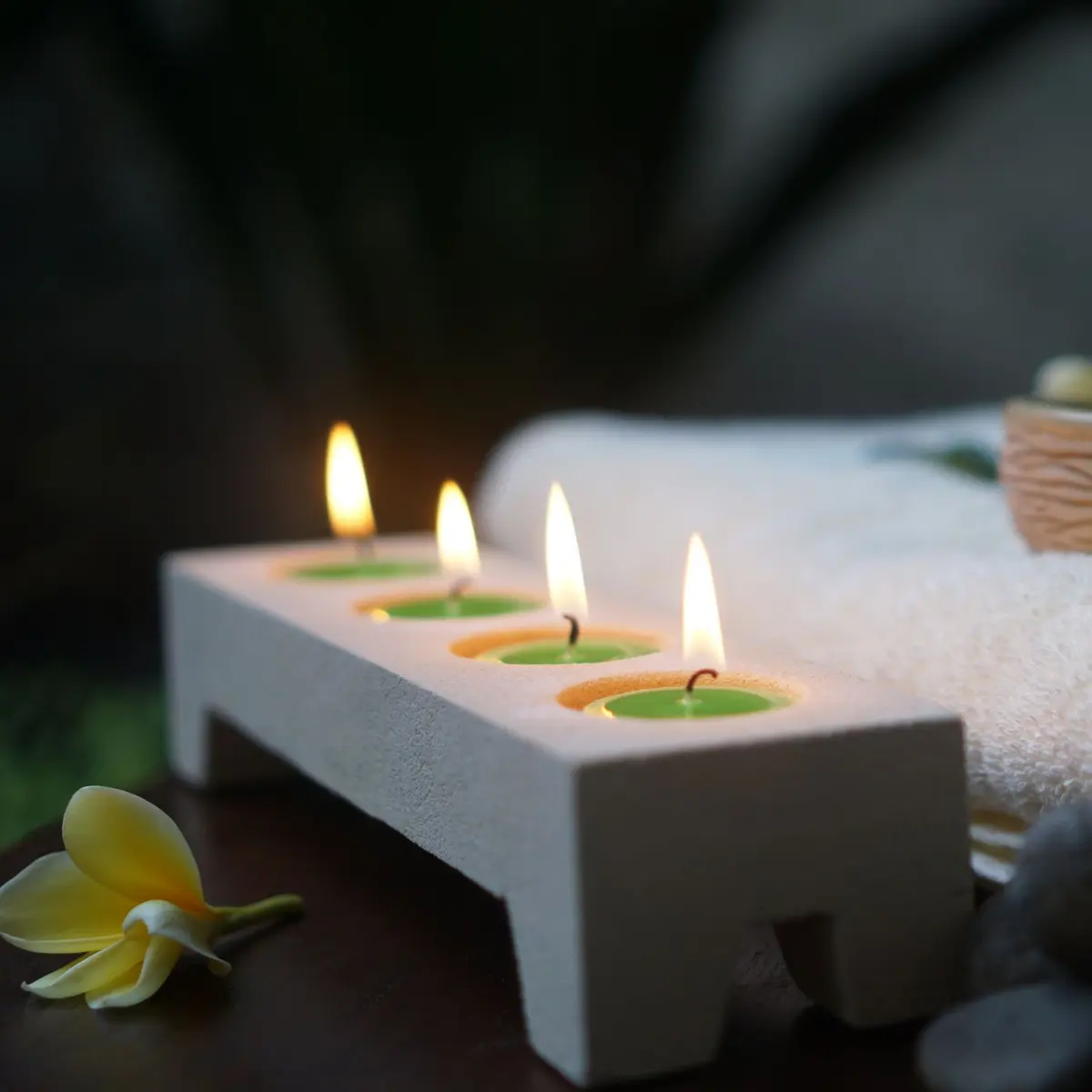 Candles, folded towels and frangipani flowers
